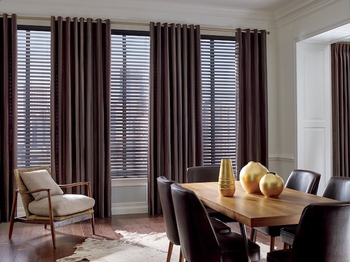 A dining room with espresso brown window coverings and chairs.